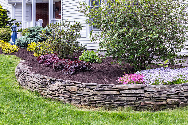 This garden terrace behind a slate rock wall has just been completely weeded and cleaned up with fresh mulch spread evenly on the ground surrounding ornamental bushes and flowers. See first related photo below for the comparison "BEFORE" this garden was restored to a properly presentable appearance. :)