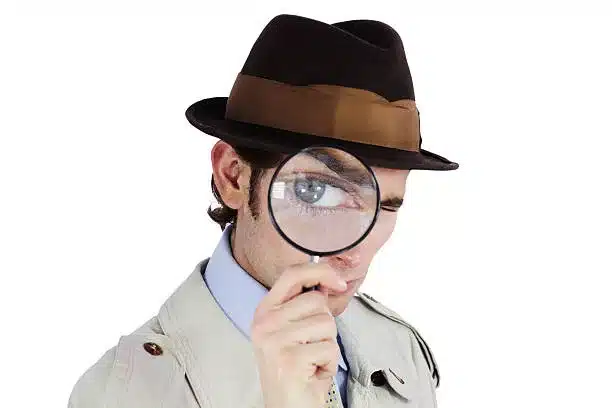 Curious private investigator looking through a magnifying glass against a white background